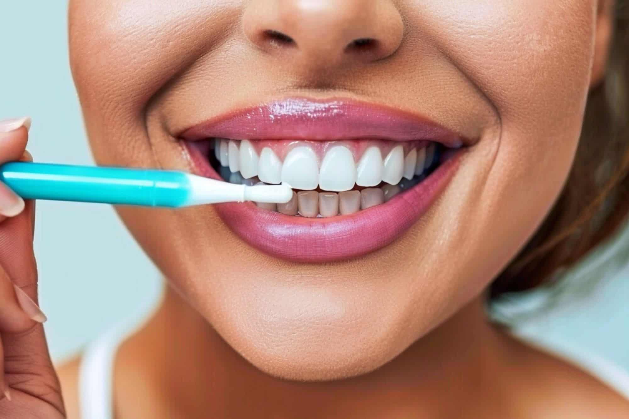 a woman is smiling and holding a teeth-whitening pen